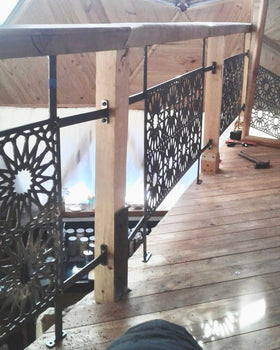 Baranda de acero calado con diseño geométrico de estrella instalada en pasillo interior de domo geodésico con piso y estructura de madera, testimonio real fabricada a medida por IronPig Chile