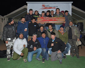 Letrero de madera con logo Raid Atacama en acero sostenido por grupo de participantes del evento de aventura en el desierto de Atacama, Chile, fabricado por IronPig