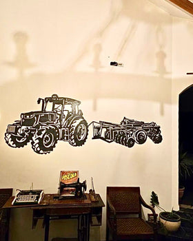 Silueta decorativa de acero negro de tractor John Deere con rastra agrícola, instalada en pared interior de sala con decoración vintage, fabricada a pedido por IronPig Chile
