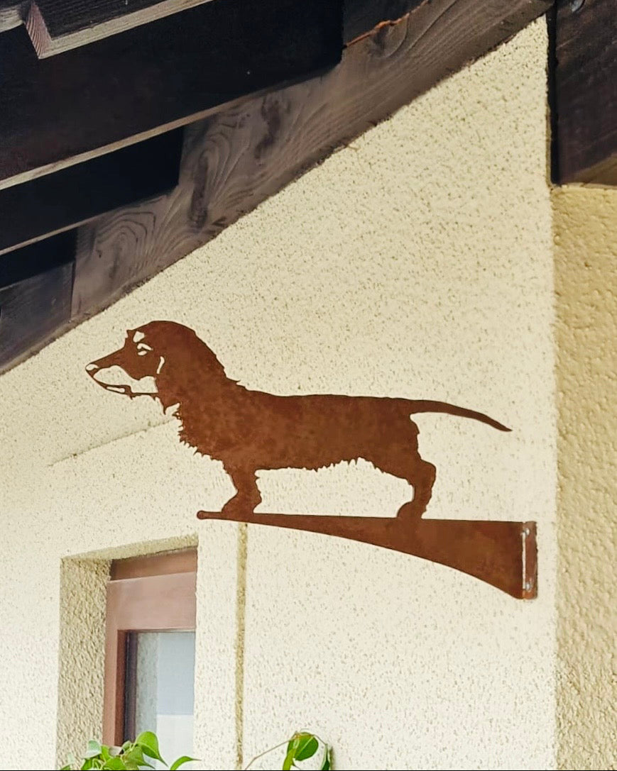 Silueta decorativa de perro salchicha en acero corten oxidado, montada en fachada exterior de casa, fabricada a medida por IronPig Chile