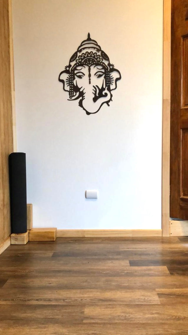 Foto de cliente con colgante Ganesha instalado en pared. Decoración en sala de yoga.